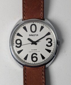 Raketa Big Zero Russo – Scatola e Cinturino Originali Importatore – Grade B 17 Orologio da polso Raketa Big Zero russo con quadrante bianco, numeri arabi neri (0, 3, 6, 9), lancette nere e cinturino in pelle marrone originale, presentato con la sua scatola originale.