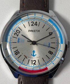 Raketa Marine 24 Ore Sovietico Vintage (Anni '80) Grade C 10 Orologio da polso sovietico Raketa Marine 24 ore vintage degli anni '80 con quadrante argentato, indicazione delle 24 ore, lunetta blu e rossa con simboli marittimi e cinturino in pelle marrone.