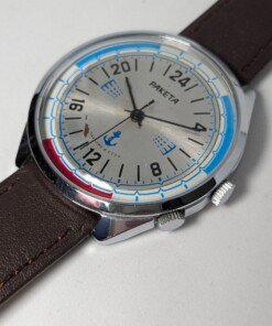 Raketa Marine 24 Ore Sovietico Vintage (Anni '80) Grade C 15 Orologio da polso sovietico Raketa Marine 24 ore vintage degli anni '80 con quadrante argentato, indicazione delle 24 ore, lunetta blu e rossa con simboli marittimi e cinturino in pelle marrone.