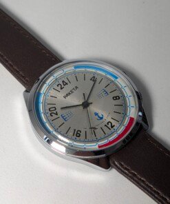 Raketa Marine 24 Ore Sovietico Vintage (Anni '80) Grade C 14 Orologio da polso sovietico Raketa Marine 24 ore vintage degli anni '80 con quadrante argentato, indicazione delle 24 ore, lunetta blu e rossa con simboli marittimi e cinturino in pelle marrone.