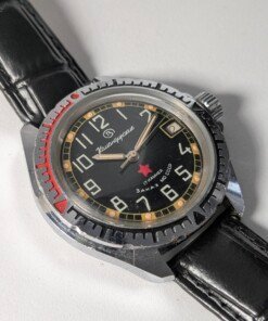 Vostok Komandirskie Zakaz MO CCCP meccanico manuale 2414 - Grade B 13 Orologio da polso militare sovietico Vostok Komandirskie Zakaz MO CCCP a carica manuale (calibro 2414) con quadrante nero, numeri arabi bianchi, lancette luminose, ghiera girevole e cinturino in pelle nera.