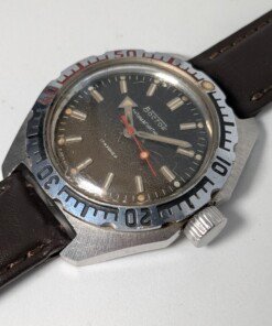 Vostok Amphibia 470 Sovietico Vintage (Anni '80) - Leggenda Subacquea Grade B 12 Orologio subacqueo sovietico vintage Vostok Amphibia 470 degli anni '80 con quadrante scuro, indici luminosi, ghiera girevole numerata e cinturino in pelle marrone.