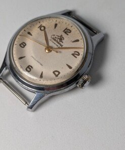 Sportivnie "Running Man" Sovietico Anni '50 Hacking Second Calibro 2634 (Ex 1MWF) - Grade B 25 Orologio da polso sovietico Sportivnie "Running Man" degli anni '50 con quadrante color crema, numeri arabi neri, lancette dorate, secondi centrali con funzione hacking e il logo dell'uomo che corre, alimentato dal calibro 2634 (ex 1MWF).