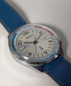 Orologio Sovietico Raketa Marine 24h con Cinturino Originale Blu - Grade B 18 Orologio sovietico Raketa Marine 24 ore anni '80 con quadrante argentato, linee blu tratteggiate per silenzio radio e cinturino blu