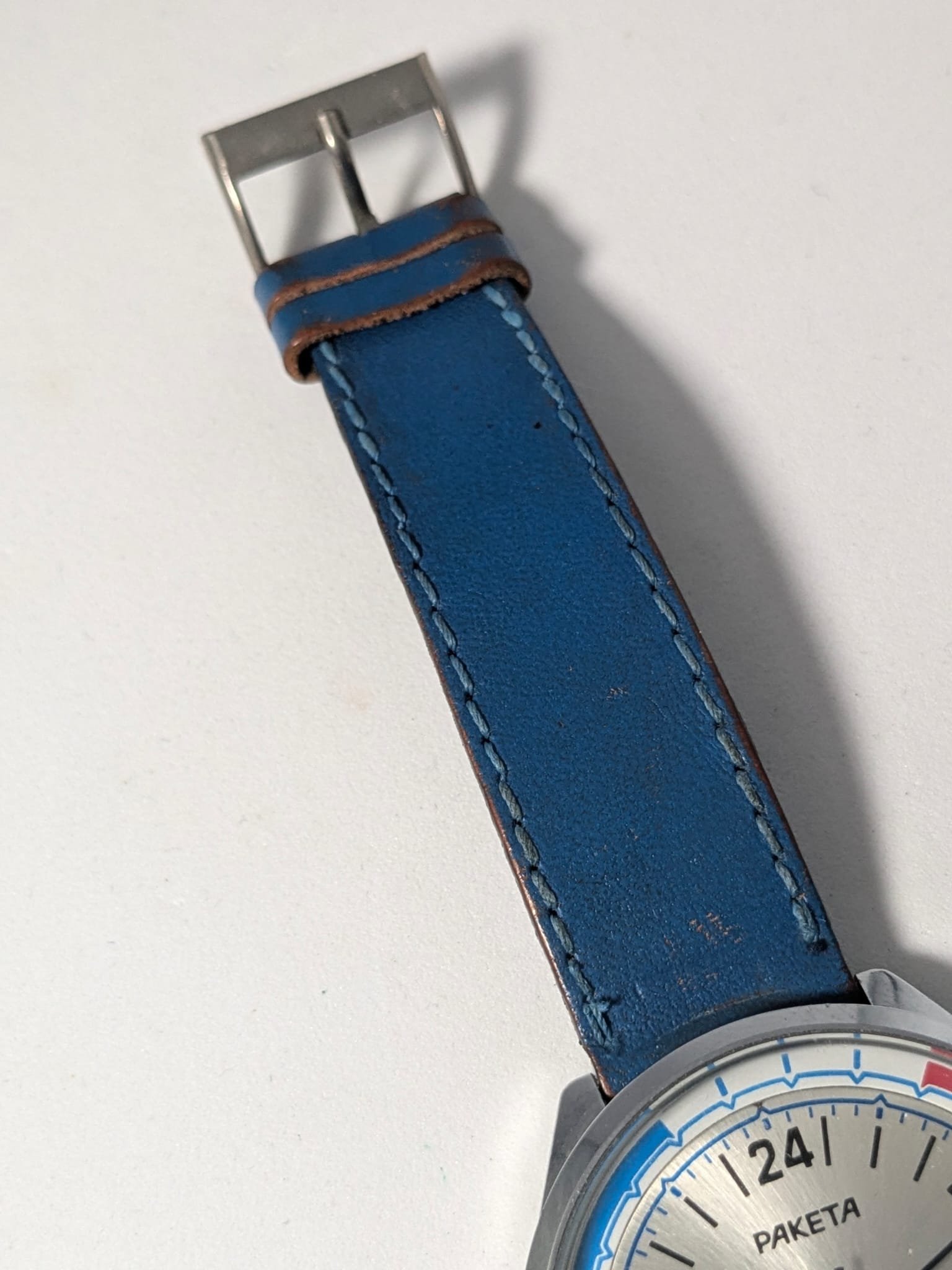 Orologio Sovietico Raketa Marine 24h con Cinturino Originale Blu - Grade B 3 Orologio sovietico Raketa Marine 24 ore anni '80 con quadrante argentato, linee blu tratteggiate per silenzio radio e cinturino blu