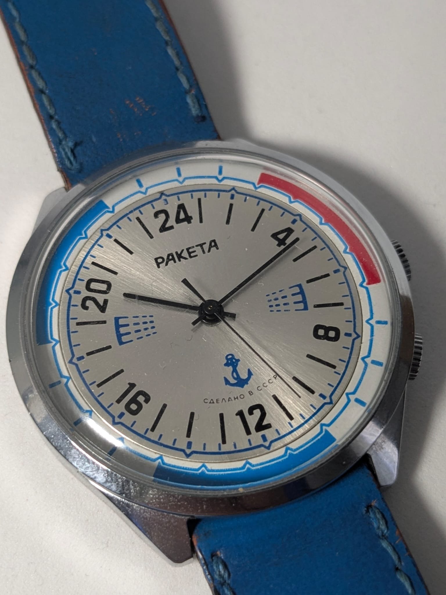 Orologio Sovietico Raketa Marine 24h con Cinturino Originale Blu - Grade B 6 Orologio sovietico Raketa Marine 24 ore anni '80 con quadrante argentato, linee blu tratteggiate per silenzio radio e cinturino blu