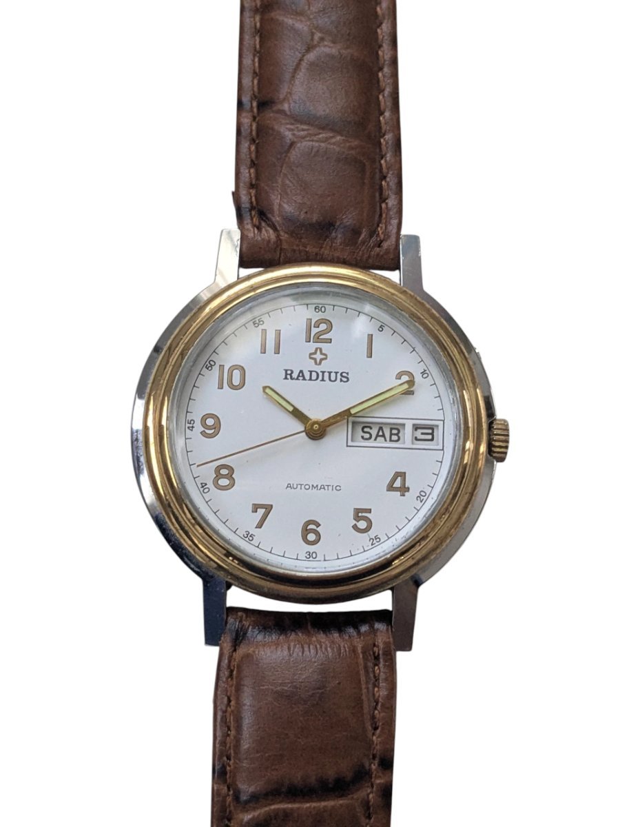 Radius Automatico Vintage Cassa Bicolore Calibro Slava 2427 – Grade B 2 Orologio automatico vintage sovietico/russo Radius, quadrante bianco, indici arabi dorati, datario giorno/data, cinturino pelle marrone.