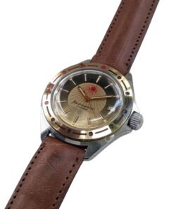 Orologio Vostok Komandirskie Rising Sun Meccanico Manuale URSS - Grade A 19 Orologio russo Vostok Komandirskie vintage ref. 130, quadrante bicolore nero/oro con stella rossa, datario, lunetta dorata, cinturino in pelle.