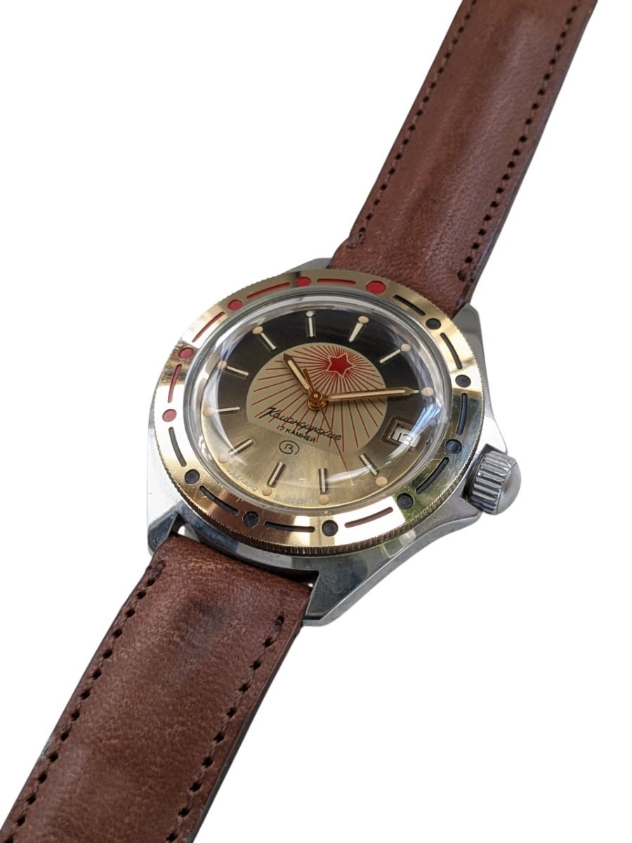 Orologio Vostok Komandirskie Rising Sun Meccanico Manuale URSS - Grade A 9 Orologio russo Vostok Komandirskie vintage ref. 130, quadrante bicolore nero/oro con stella rossa, datario, lunetta dorata, cinturino in pelle.