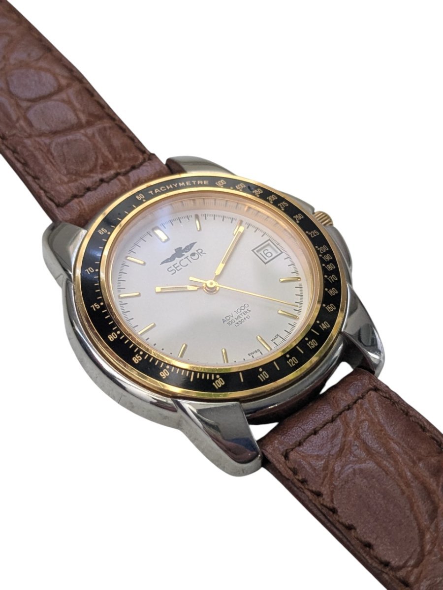 Orologio Sector ADV 1000 Quartz Anni ’90 Tachimetro Swiss Made - Grade B 9 Orologio vintage Sector ADV 1000 Swiss Made con quadrante bianco, datario, lunetta tachimetrica nera e cinturino in pelle marrone.