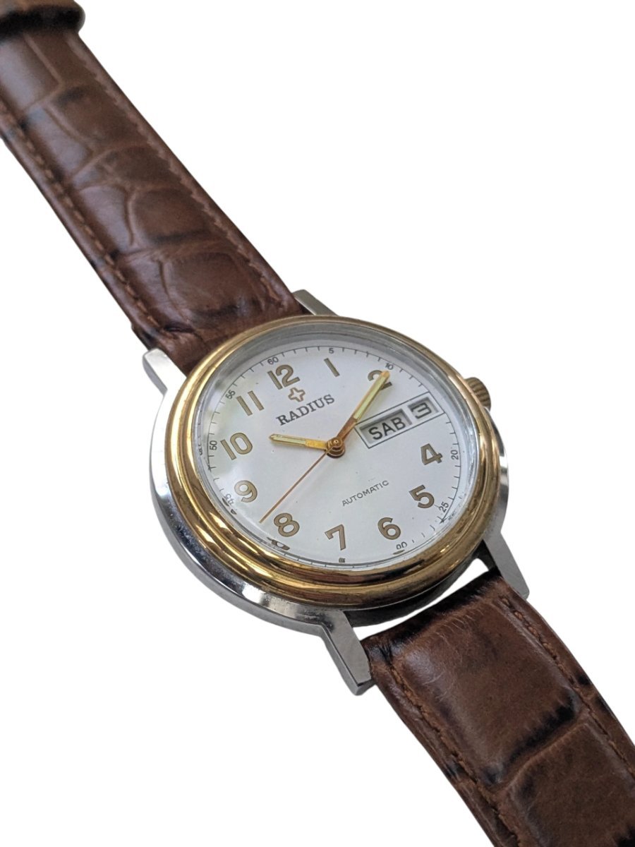 Radius Automatico Vintage Cassa Bicolore Calibro Slava 2427 – Grade B 7 Orologio da collezione sovietico vintage Radius automatico, con cassa bicolore, quadrante bianco giorno/data e cinturino in pelle marrone.